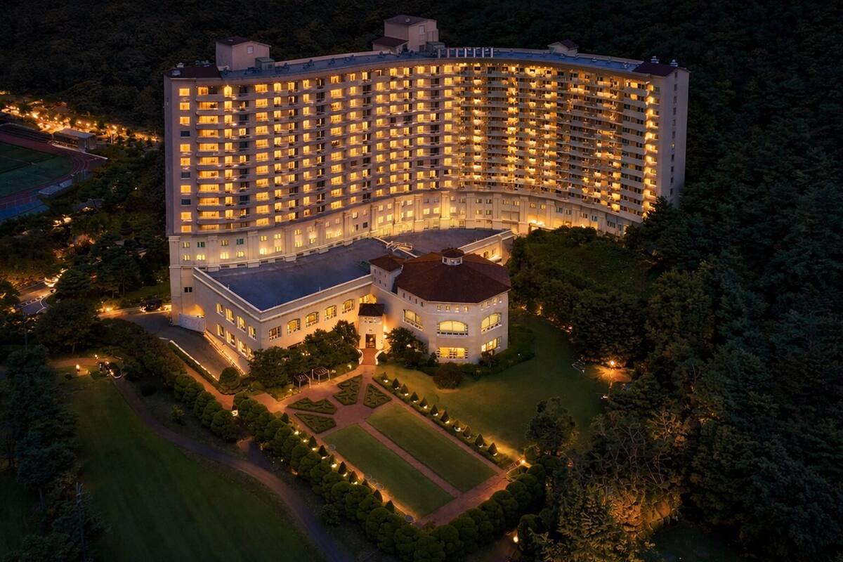 A large, multi-story hotel with a central courtyard, surrounded by lush greenery.