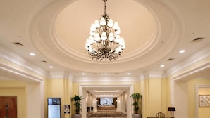 A hotel lobby with a grand chandelier, a reception desk, and a large carpeted area leading to a hallway. - La Vie Dor Hotel and Resort, Trademark Collection by Wyndham (Hwaseong)