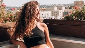 A person leaning on a balcony railing with a cityscape in the background. - The Post Hostel (Jerusalem)