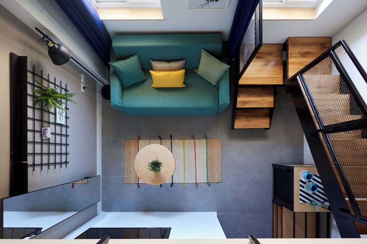 A modern interior with a teal sofa, a round table, and a staircase.