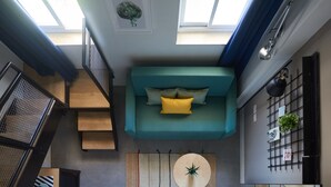 A modern interior with a teal sofa, wooden staircase, and a wall-mounted plant. - The Post Hostel (Jerusalem)