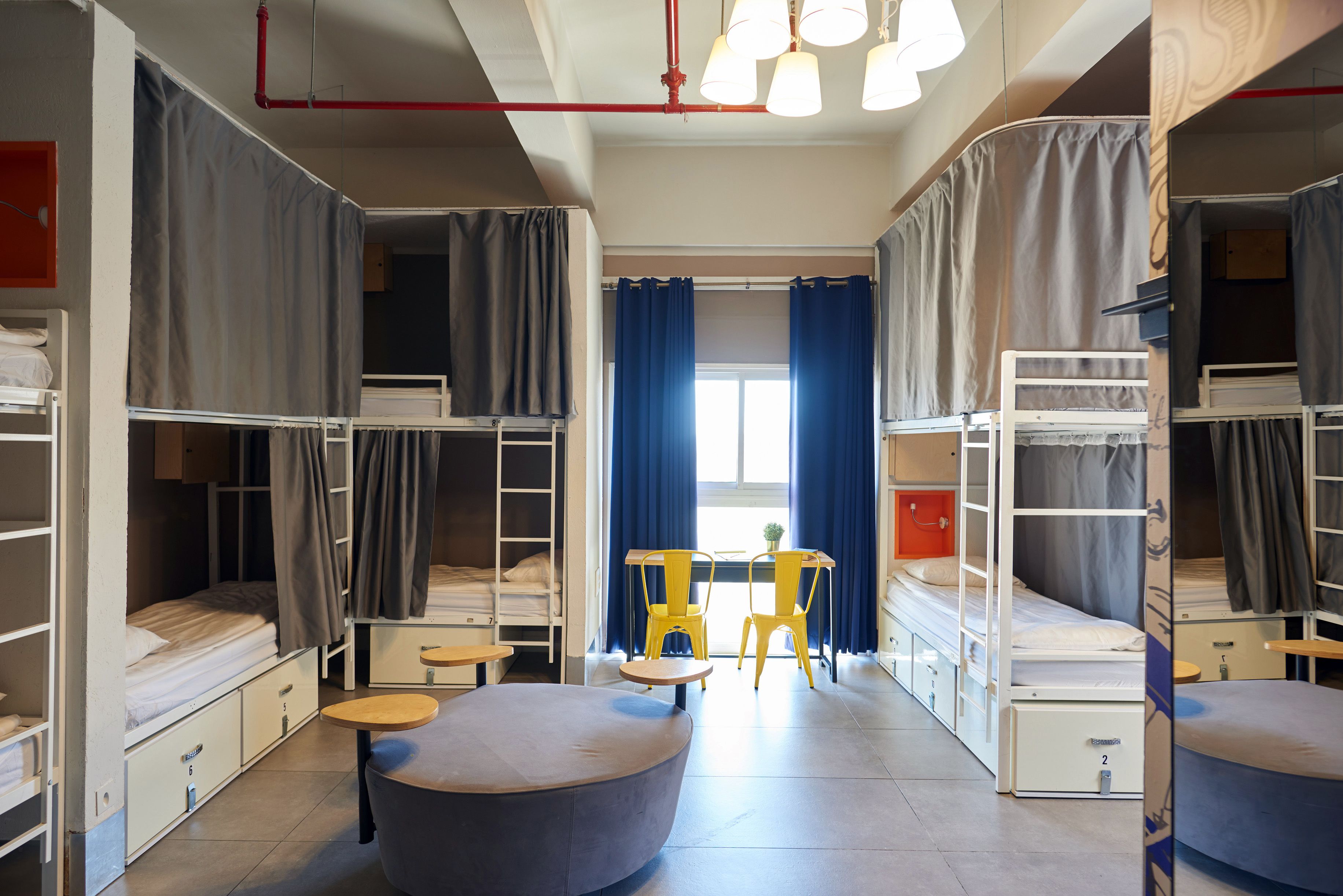A dormitory room with bunk beds, a round table, and chairs.