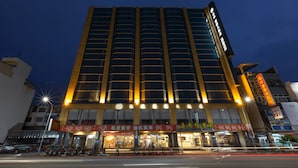 A high-rise hotel with multiple floors, large windows, and illuminated signage.