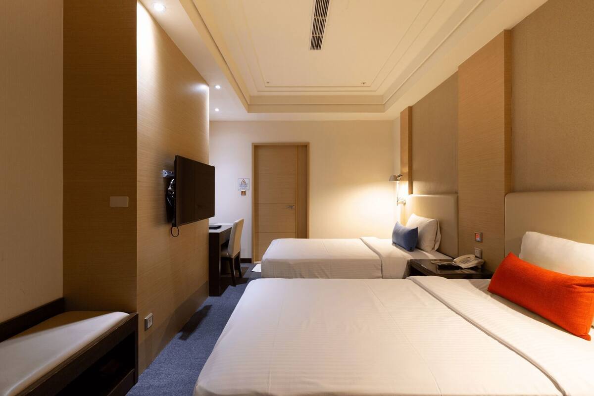 Ein Hotelzimmer mit zwei Betten, einem Schreibtisch, einem Fernseher und einem Telefon.