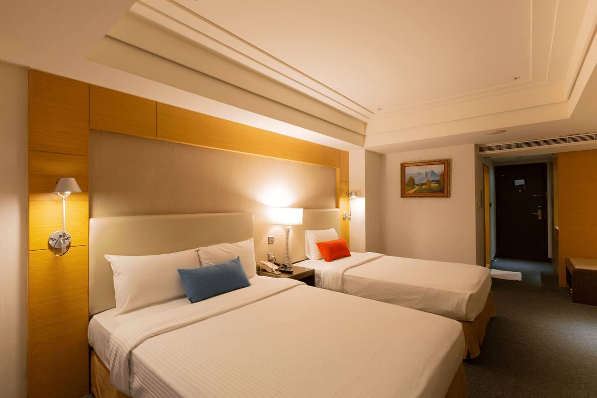 Ein Hotelzimmer mit zwei Betten, einem Nachttisch, einer Lampe und einem Bild an der Wand.