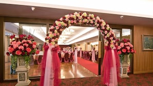A grand entrance with a floral archway, a red carpet, and a mirrored wall reflecting the room.