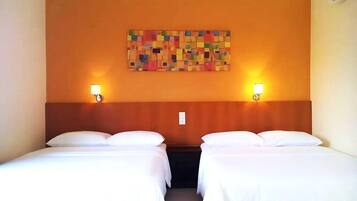 A hotel room with two beds, a wooden headboard, a colorful abstract painting on the wall, and two wall-mounted lamps.