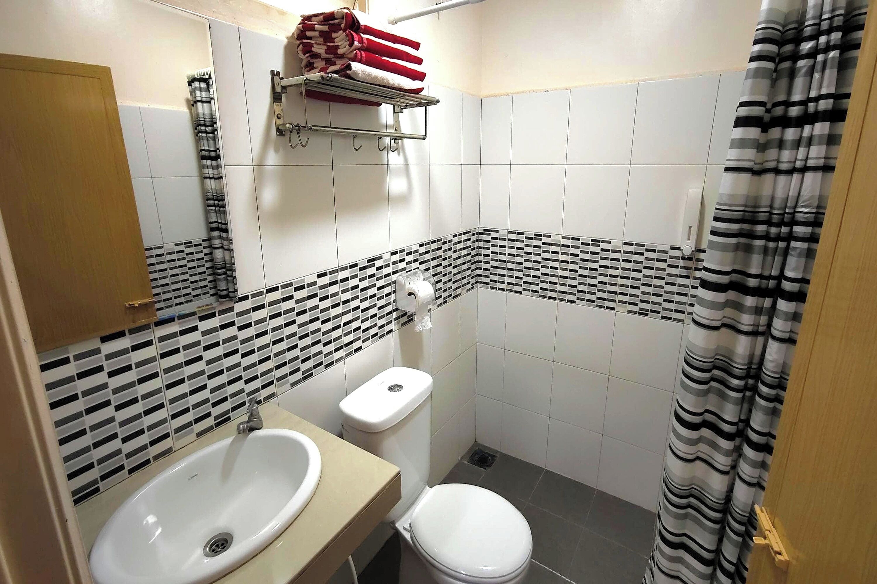A bathroom with a white sink, toilet, and shower curtain.