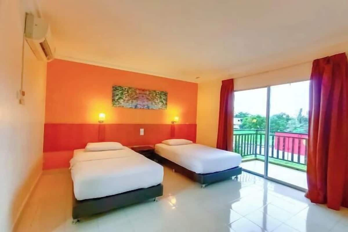 Una habitación de hotel con dos camas, un cuadro en la pared y un balcón con vistas.