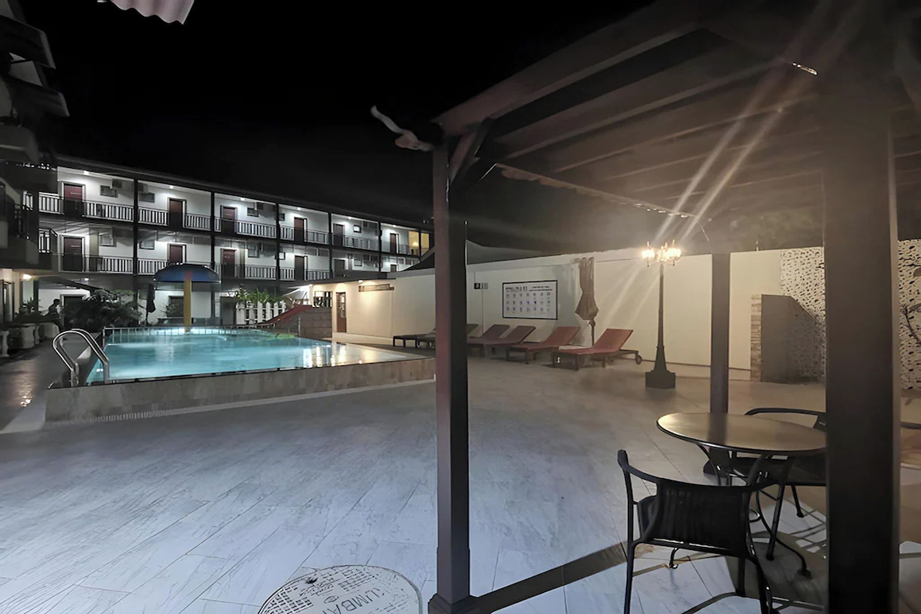 A pool area with a covered seating area, a building with multiple balconies, and a poolside bar.