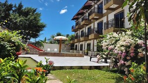 Ein mehrstöckiges Hotel mit Balkonen, einem Spielbereich für Kinder und üppiger Bepflanzung.