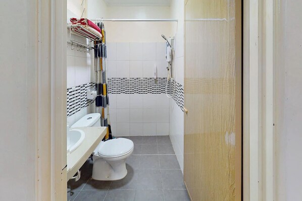 Een kleine badkamer met toilet, wastafel en douche.