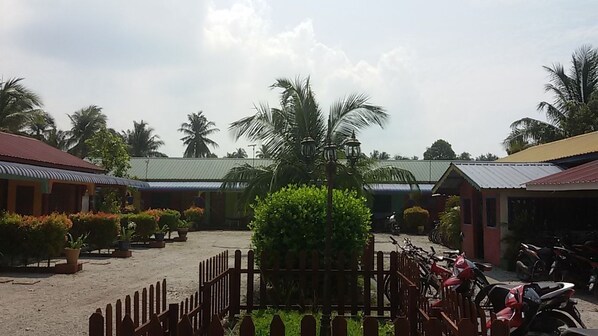 A courtyard with a paved area, potted plants, a wooden fence, and several motorcycles parked.
