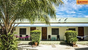 A building with a corrugated metal roof, multiple windows, and a small porch area with chairs and a hammock. - Rainbow Lodge Langkawi (Langkawi)