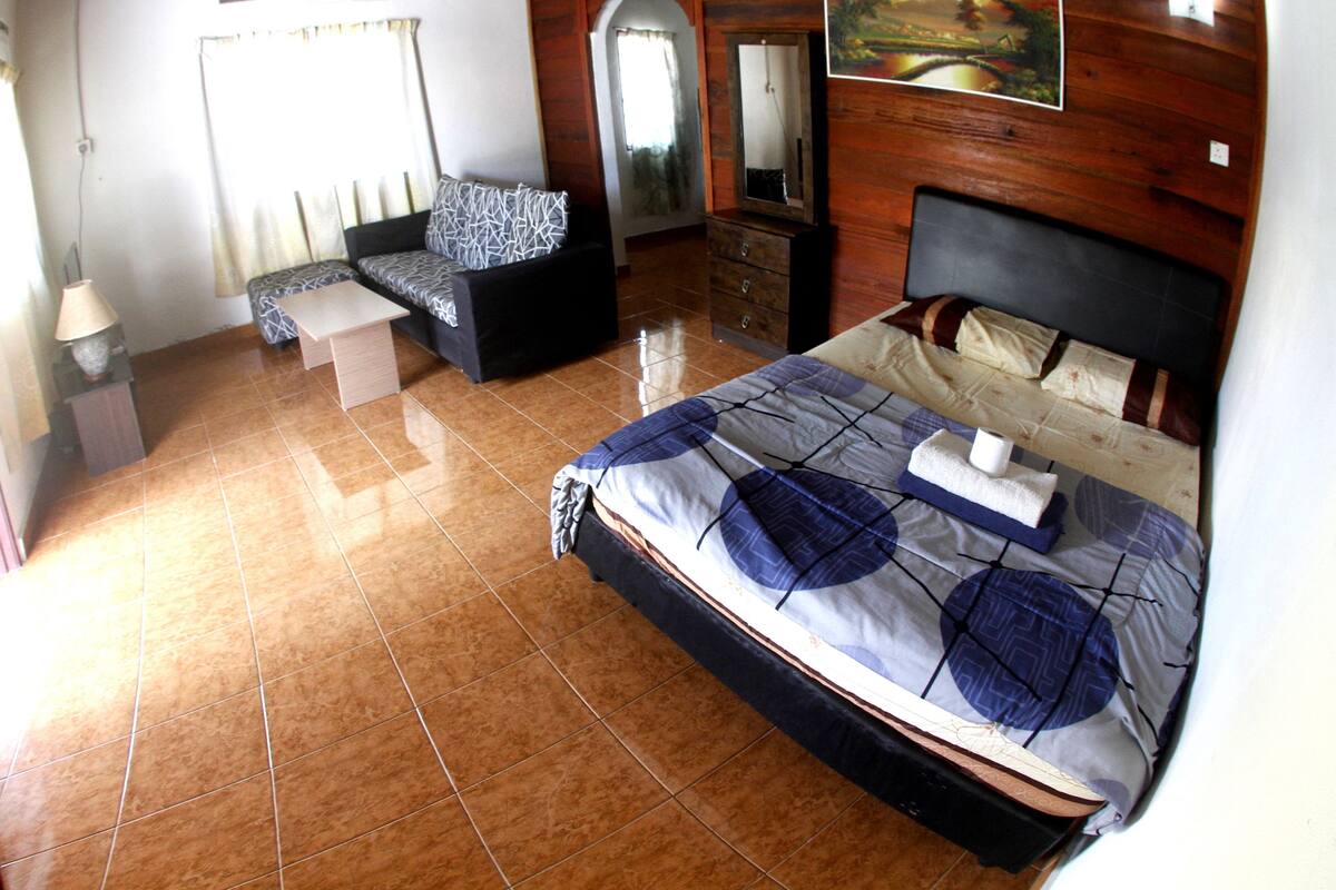 A bedroom with a bed, a sofa, a dresser, and a mirror.