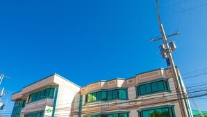 Un immeuble à plusieurs étages, doté d’une façade sobre, de grandes fenêtres et d’un espace de stationnement où sont garées plusieurs voitures.