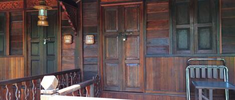 A wooden interior with two doors labeled "Villa 101" and "Villa 102," a metal railing, and a small table.