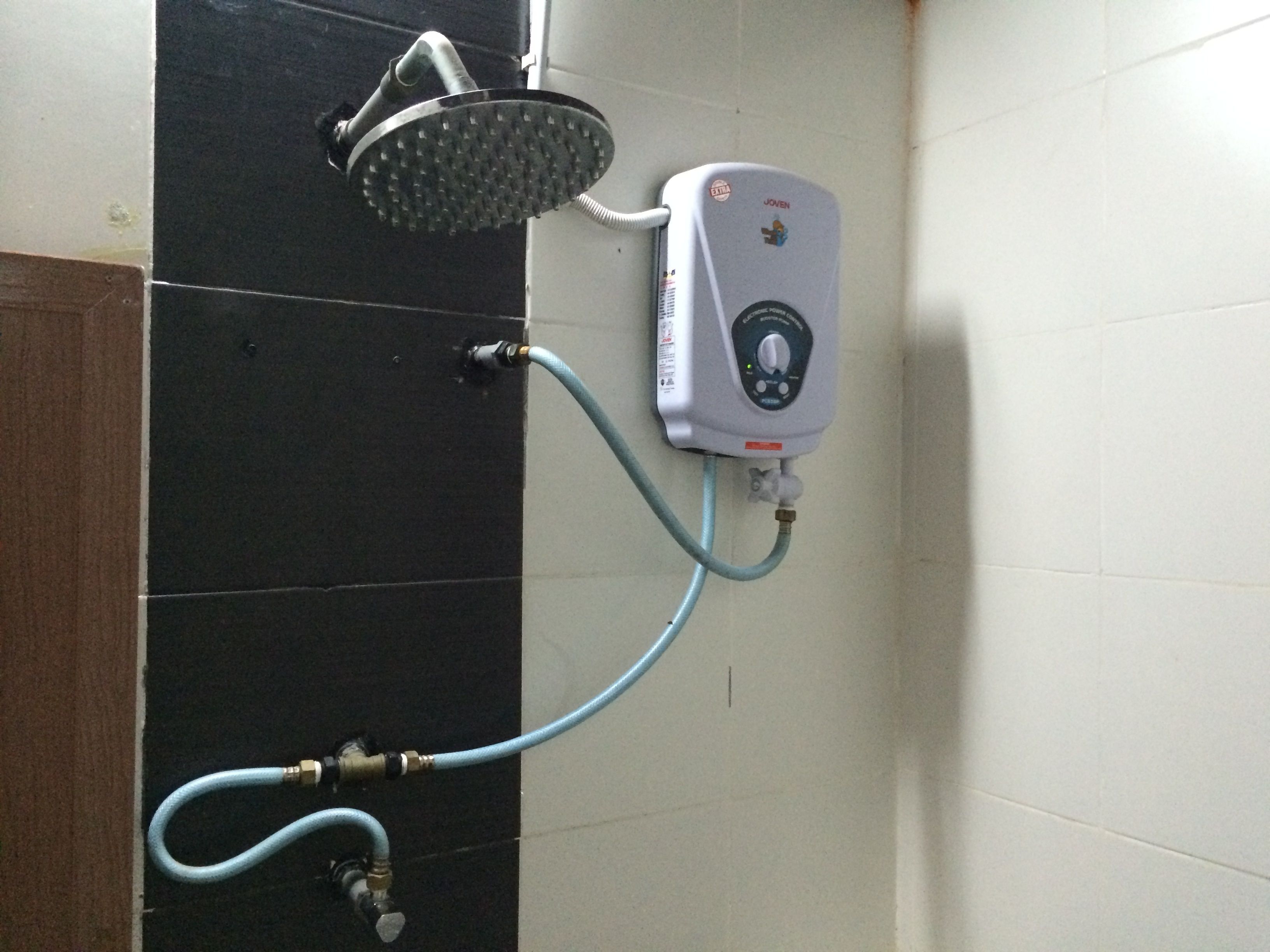 A shower with a handheld showerhead and a wall-mounted control panel.