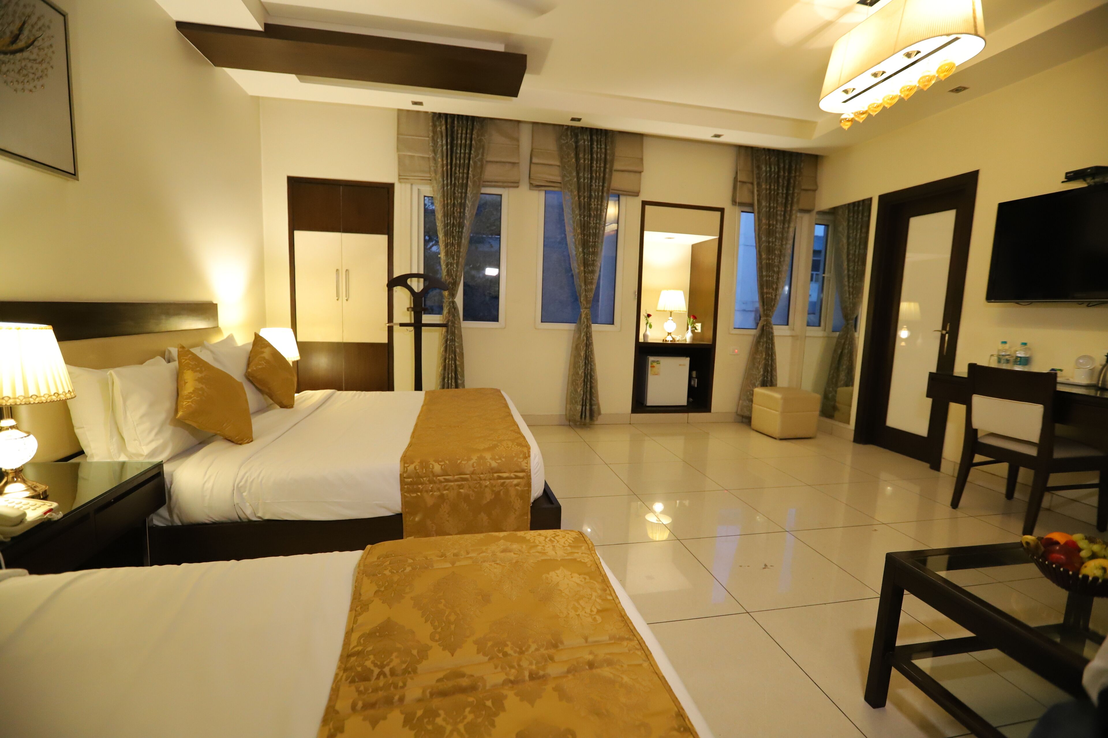 A hotel room with two beds, a TV, a desk, and a chair.
