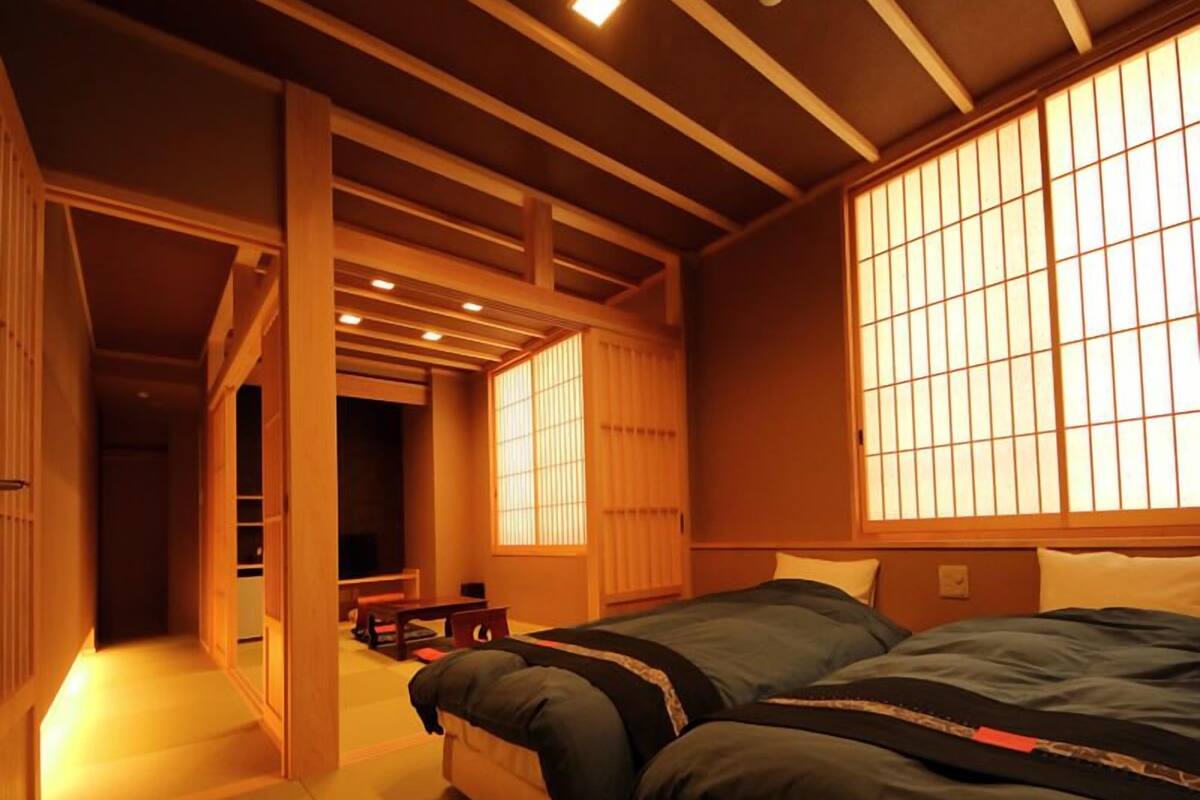 Ein traditioneller japanischer Raum mit Tatami-Boden, niedriger Decke mit Holzbalken und verschiebbaren Shoji-Bildschirmen.
