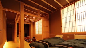 Una habitación de estilo japonés tradicional con suelo de tatami, techo bajo con vigas de madera y puertas correderas shoji.