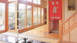 Una habitación amplia con ventanas grandes, un paraguas rojo tradicional y un letrero con caracteres japoneses.