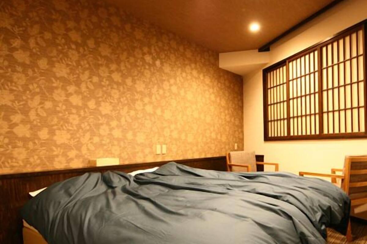 Ein Schlafzimmer mit Bett, einem Fenster mit Gitterstäben, einer Wand mit Muster und einem Holzboden.