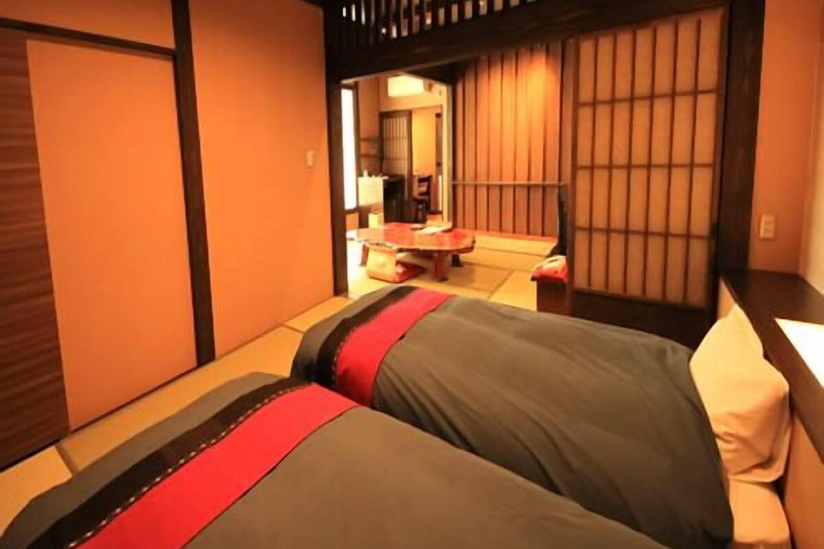 Ein Hotelzimmer mit zwei Betten, einem kleinen Tisch und einer traditionellen japanischen Schiebetür.