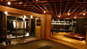 Amplia habitación con techo de madera y grandes puertas correderas de vidrio que dan a un balcón.