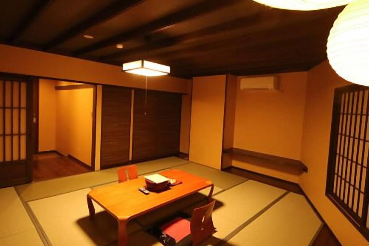 Ein traditioneller japanischer Raum mit Tatami-Bodenbelag, einem niedrigen Holztisch und einer Schiebetür.