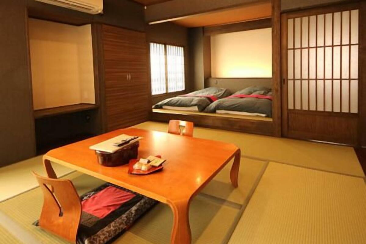 Ein traditioneller japanischer Raum mit Tatami-Bodenbelag, einem niedrigen Holztisch und einem Futon.