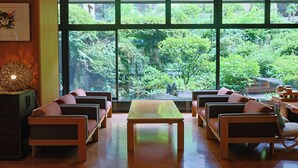 A room with a large window, wicker furniture, and a wooden table.
