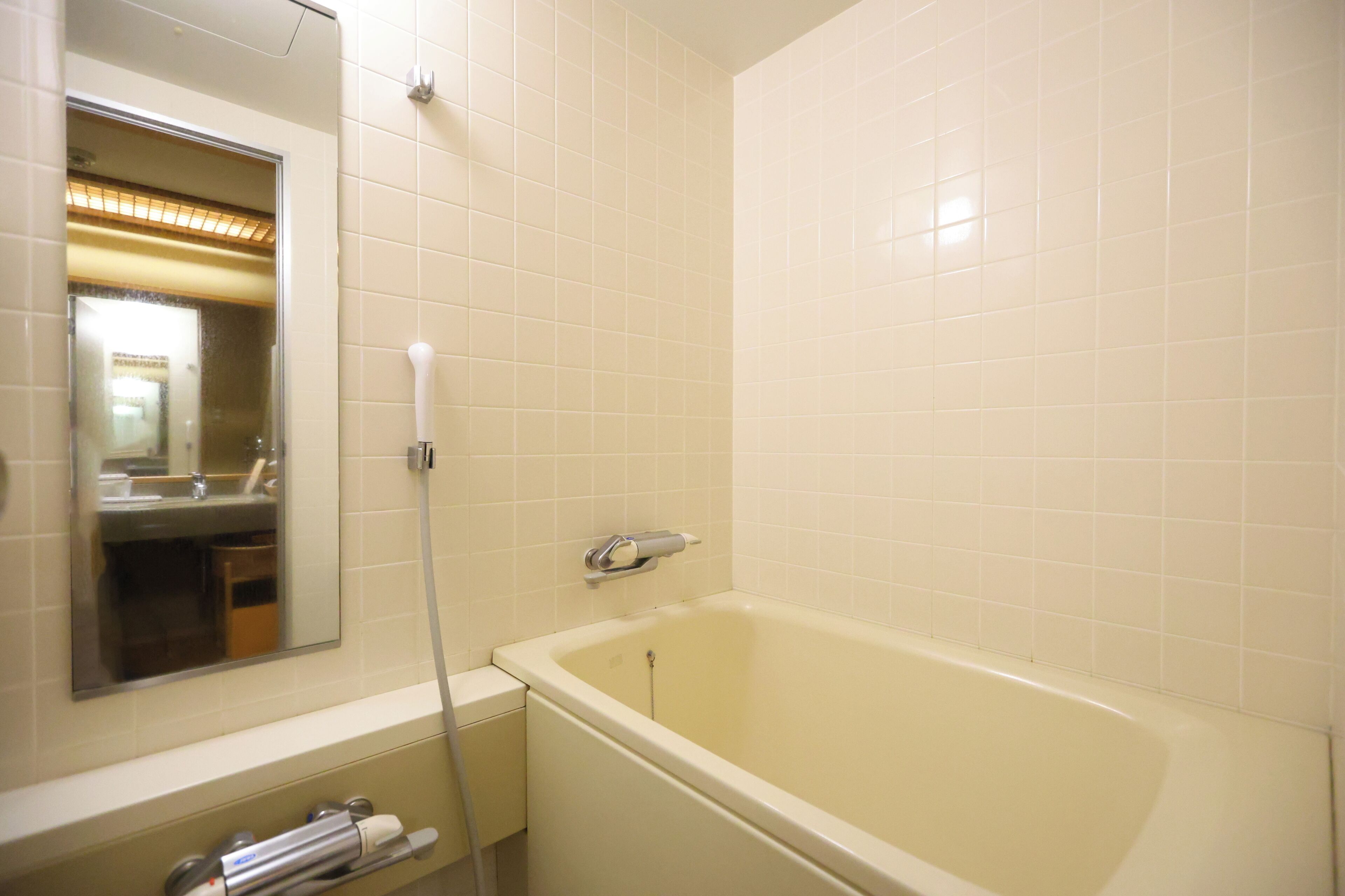 A bathroom with a bathtub, a mirror, and a towel rack.