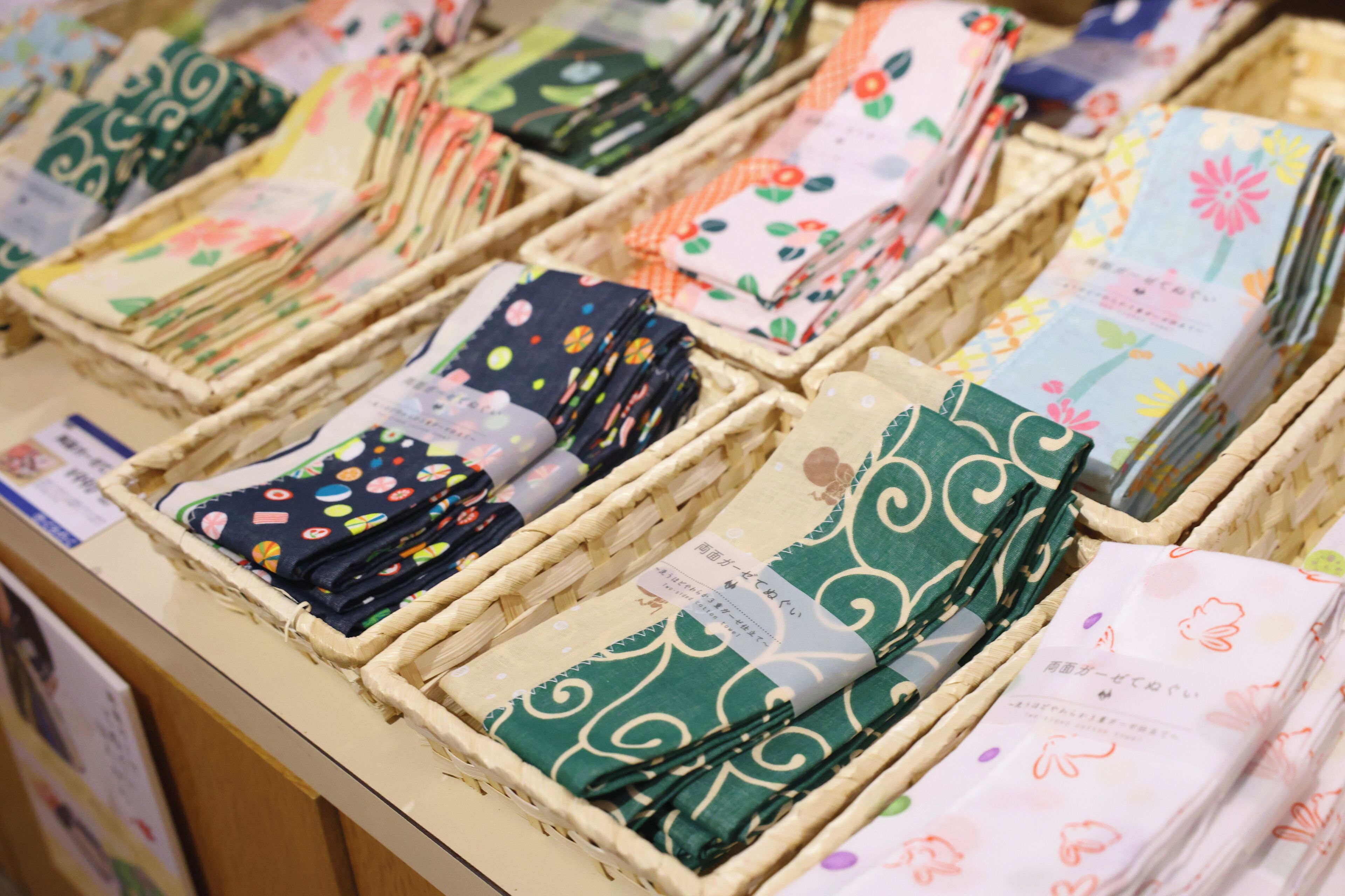 A display of neatly arranged fabric samples in wicker baskets, each with a label.