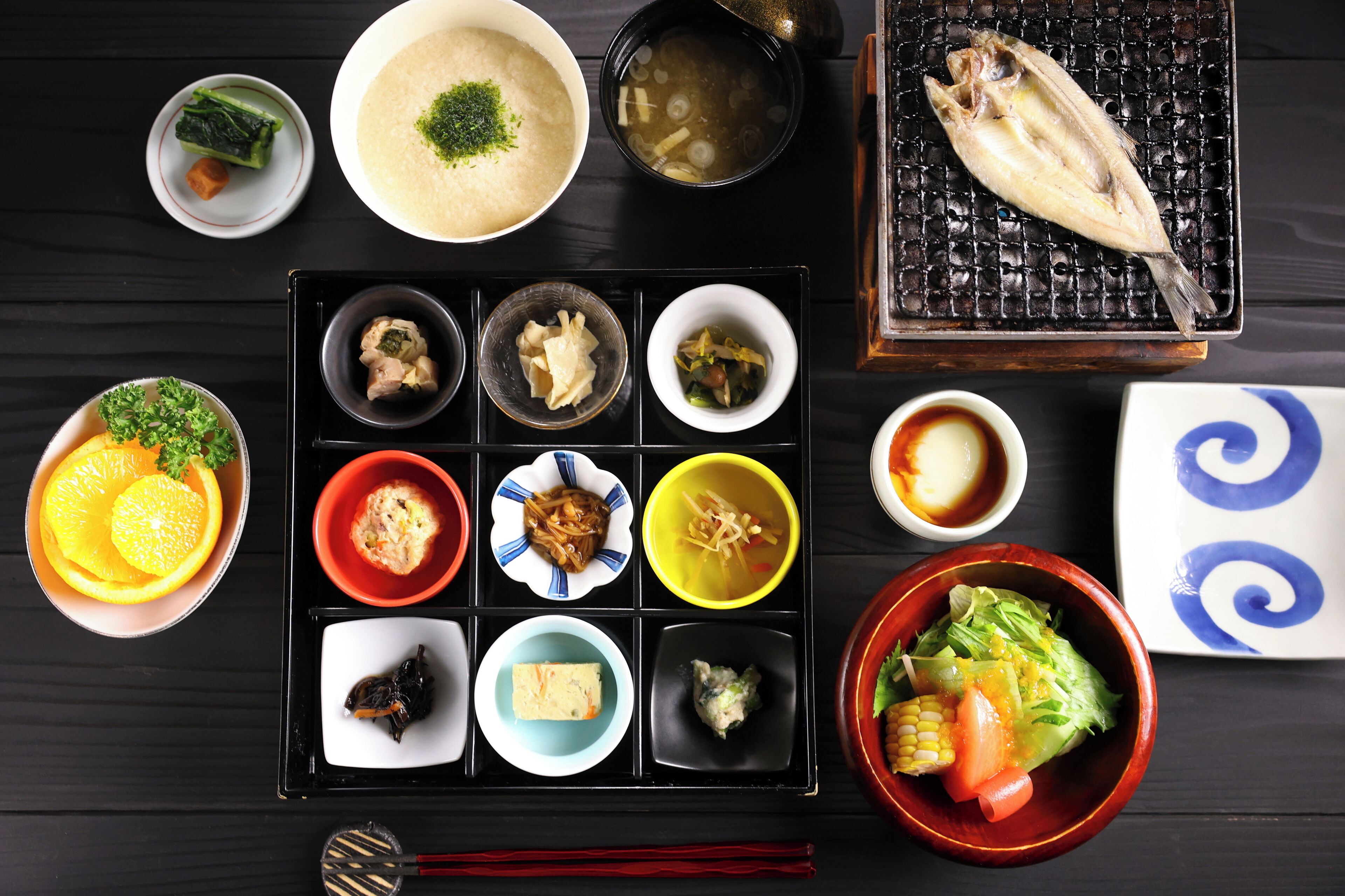 Eine traditionelle japanische Mahlzeit mit verschiedenen Gerichten, darunter Fisch, Gemüse und Suppe.