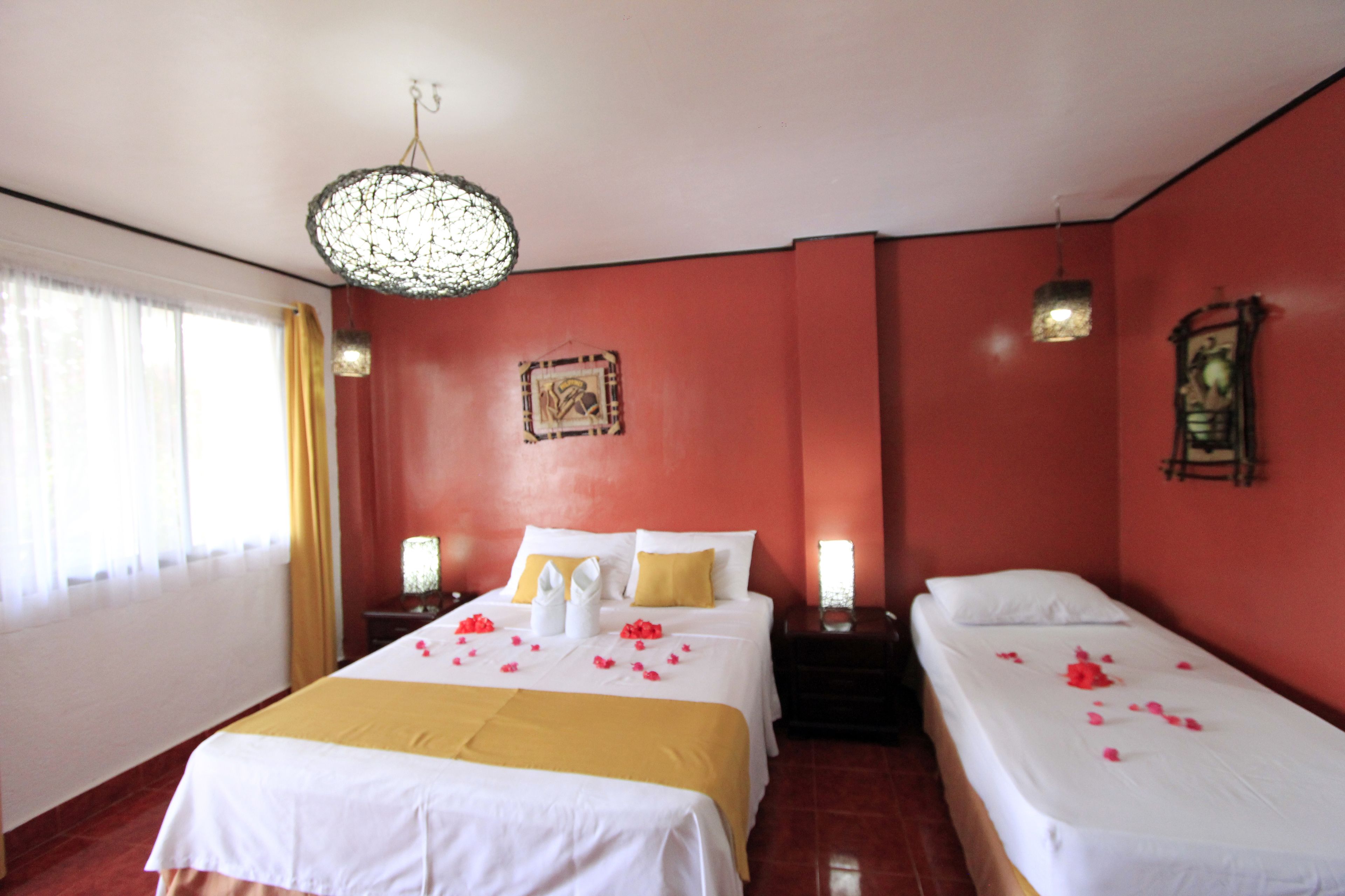 A hotel room with two beds, a chandelier, and a red wall.