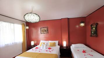 A hotel room with two beds, a chandelier, and a red wall.