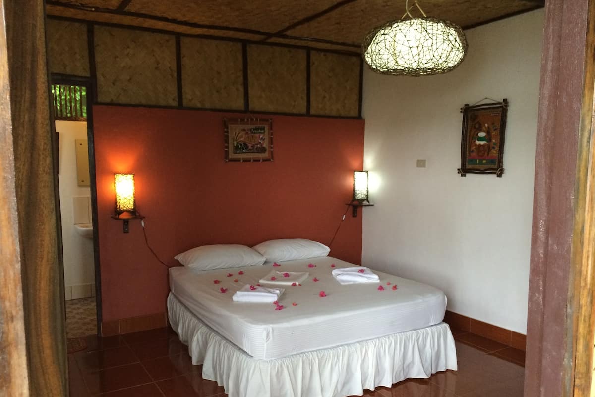 A neatly made bed with white linens, two wall-mounted lamps, and a decorative light fixture above.
