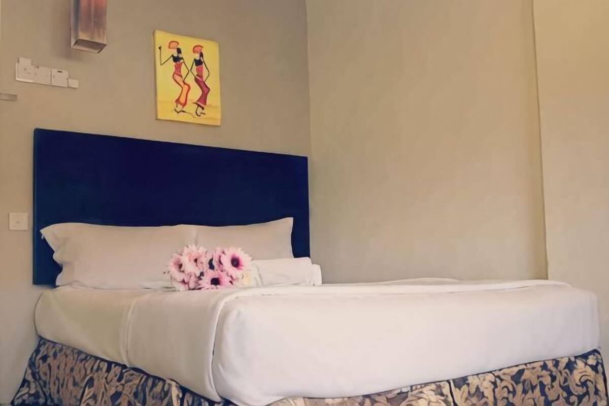 Une chambre d’hôtel avec un grand lit, une tête de lit et une œuvre d’art accrochée au mur.