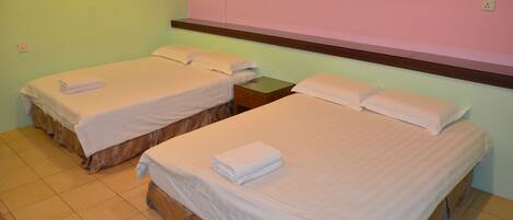 A hotel room with two beds, each with a neatly folded white towel.