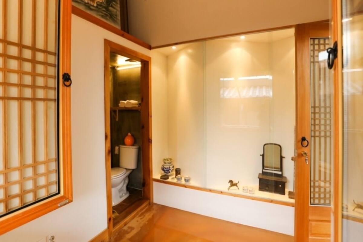 Ein traditioneller japanischer Raum mit Tatami-Böden, einer Schiebetür und einem kleinen Regal mit Dekoration.