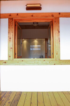 A wooden-framed window with a glass door, a wooden deck, and a ceiling light fixture. - TREGA Museum Guesthouse (Jeonju)