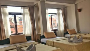 Ein Hotelzimmer mit zwei Betten, beiger Bettwäsche und Vorhängen.