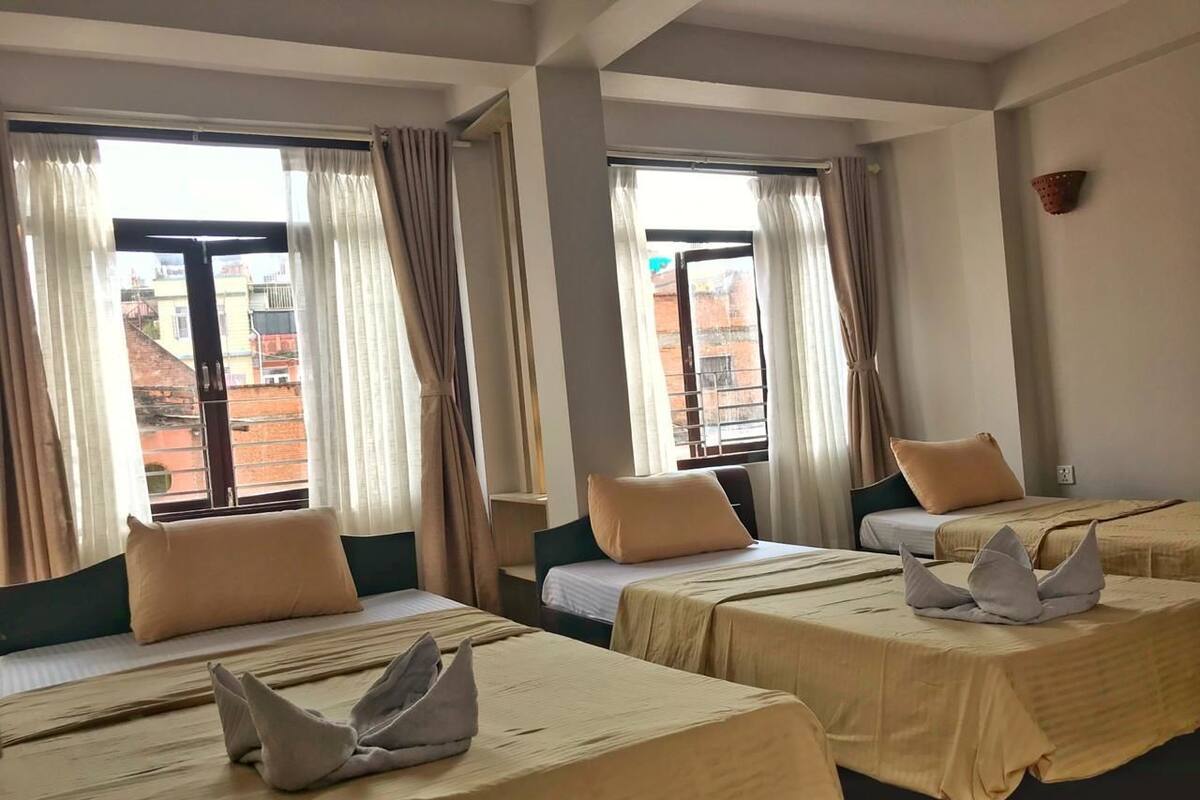 A hotel room with two beds, beige bedding, and curtains.
