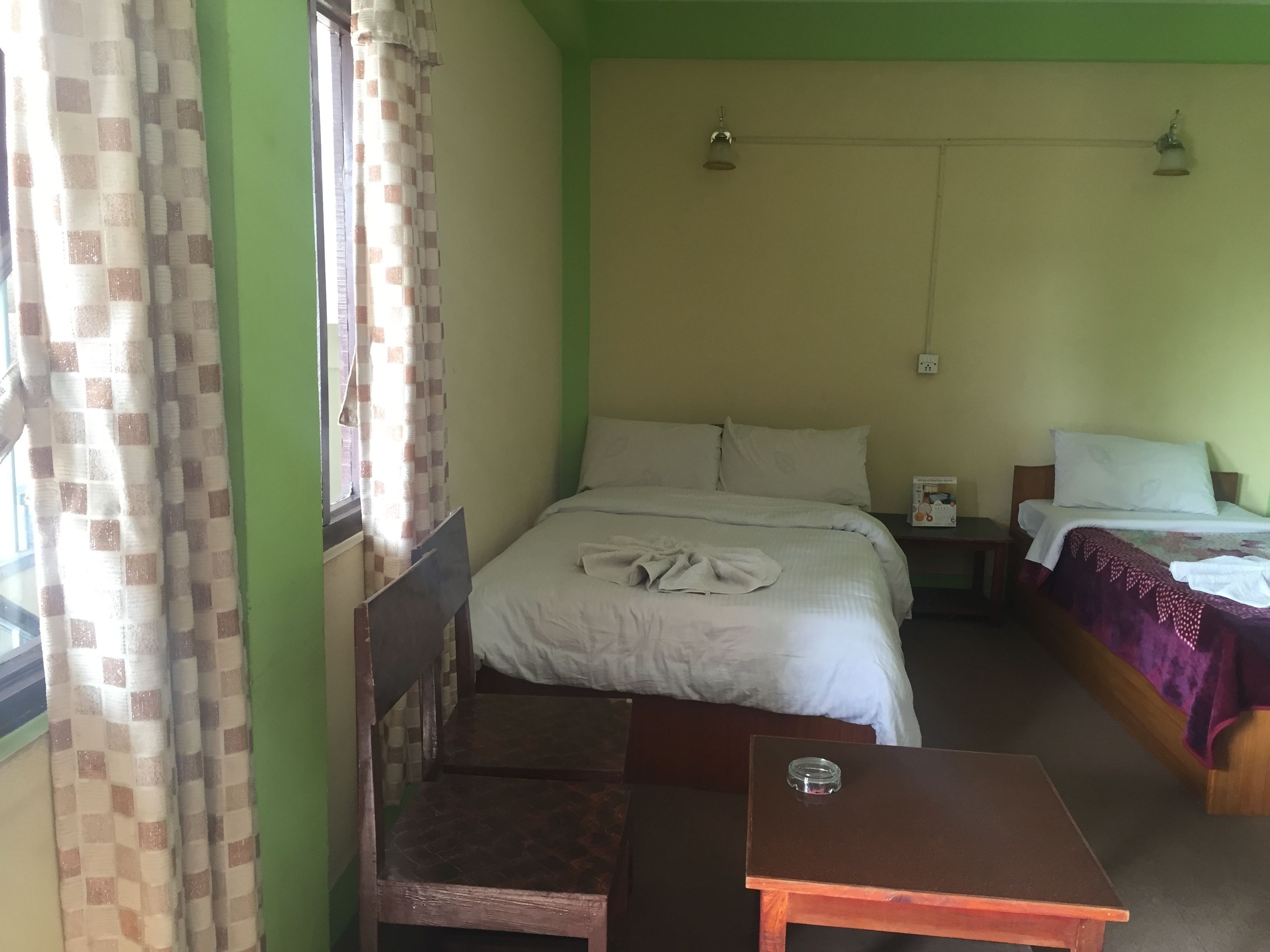 Um quarto com uma cama, uma mesa pequena e uma janela com cortinas.