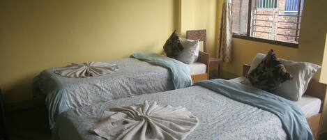 A room with two beds, each with a floral bedspread and a towel arranged in a bow shape.
