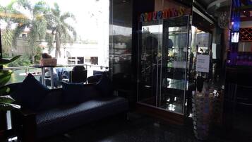 A seating area with a sofa and chairs, a glass storefront with 'SOUVENIRS' signage, and a 'Corkage Fee Php 500.00' sign.
