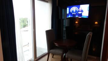 Une chambre d’hôtel avec un balcon, une télévision et deux fauteuils.