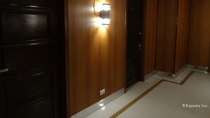 Un pasillo con paredes de madera, una lámpara fijada a la pared y una puerta con la indicación B-402.