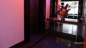 Un vestíbulo moderno con suelo de mármol, un mostrador de recepción de vidrio y un jarrón con flores.
